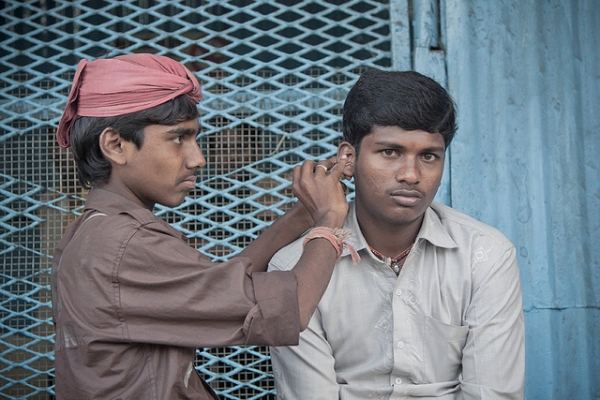 A professional ear cleaner, locally known as a "kaan saaf-wallah" with his client in Wadi Bunder, Bombay, India on March 1, 2012. (Meena Kadri/Flickr)