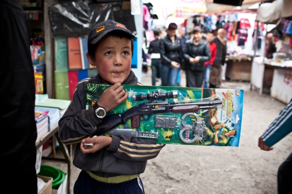 A young Kyrgyz boy clutches his new unopened toy gun in Osh Bazaar. (Sue Anne Tay)