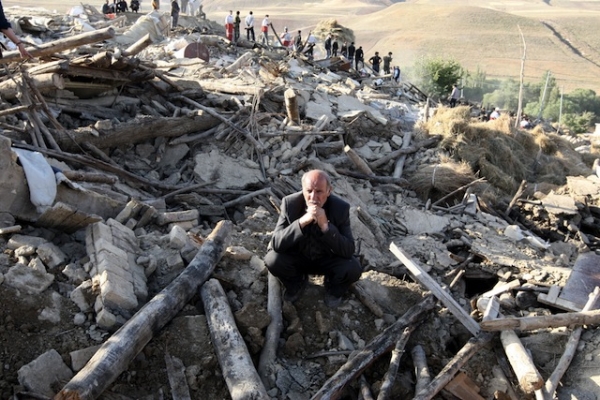 A man squats in the wreckage of his home in Baje-Baj, Iran after twin earthquakes hit the country's northwestern region on August 11, 2012. (Atta Kenare/Getty Images)