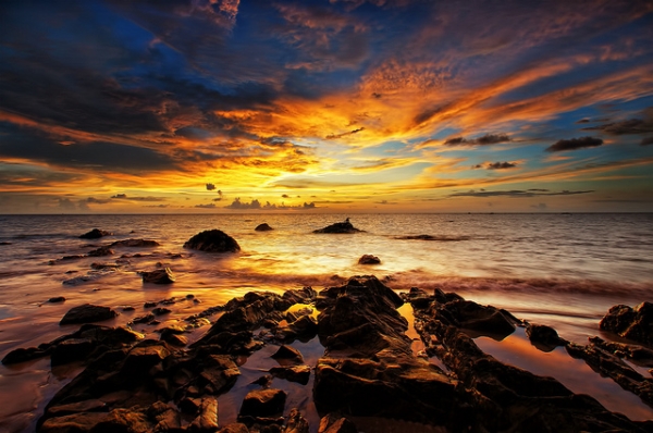 The sun sets over the rocky waters in Labuan, Malaysia on May 28, 2012. (SaturatedEyes/Flickr)