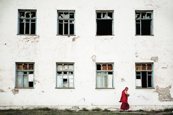 A monk walks past an abandoned Soviet-era building on the outskirts of Ulaanbaatar. (Taylor Weidman)