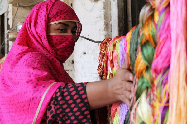 An Afghan refugee smoothes down a row of spun thread in Pakistan on January 31, 2013. (U.S. Embassy Pakistan/Flickr)