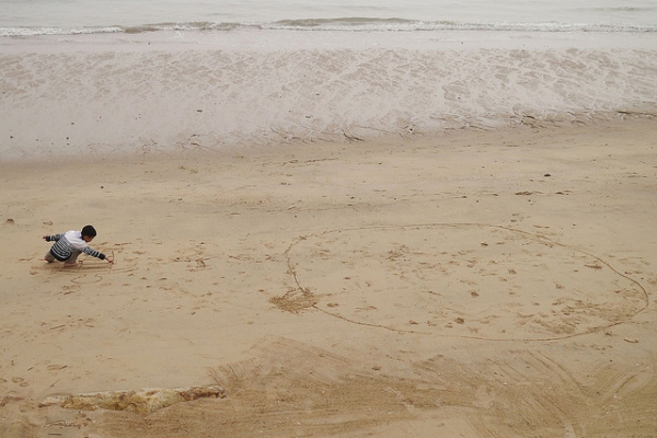 A young boy draws in the sand at the beach in Xiamen, China on February 4, 2013. (marco bono/Flickr)