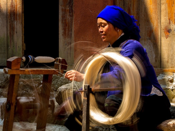 A woman makes thread at a hand operated spindle in Yunnan, China on March 25, 2013. (V-A-K/Flickr)
