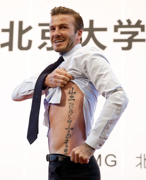 British football player David Beckham shows his tattoo to fans during his visit to Peking University on March 24, 2013 in Beijing, China. (Lintao Zhang/Getty Images) 