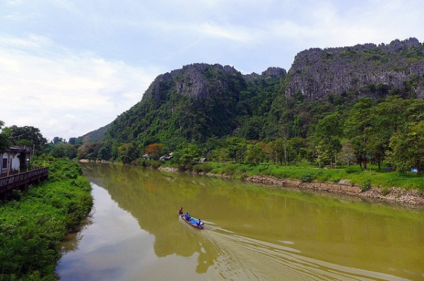 A boat full of people glide smoothly over the waters of the Nam Song river in Vang Vieng, Laos on May 18, 2013. (Madeleine_H/Flickr)