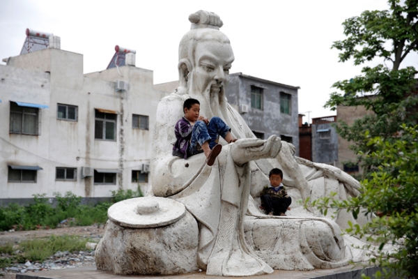 Two children play on a statue outside a factory in Shifosi town, the biggest jade center in the world in Henan, China on May 31, 2013. (Lintao Zhang/Getty Images)