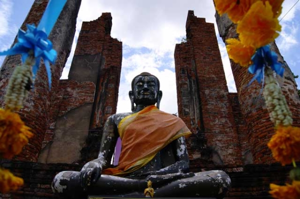 A miniature golden Buddha sits in front of a giant Buddha statue surrounded by old columns in Ayutthaya, Thailand in September 2013. (Daniel Jarrett)