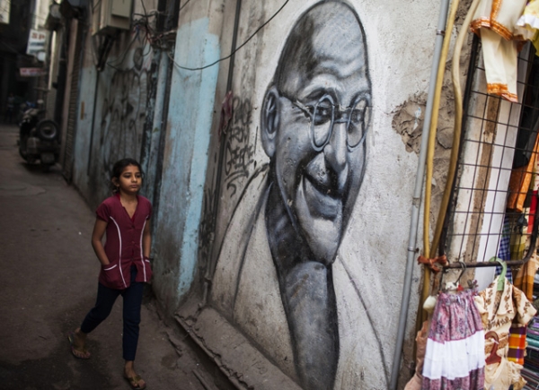 A girl walks past a painting of Mahatma Gandhi in an alleyway in New Delhi, India on March 17, 2013. (Andrew Caballero-Reynolds/AFP/Getty Images)