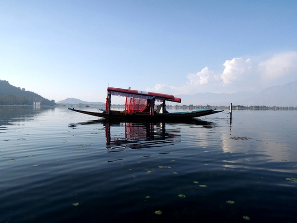 A red boat, also called a "shikara" is anchored in calm waters at Dal Lake, Kashmir on November 1, 2013. (BOMBMAN/ Flickr)