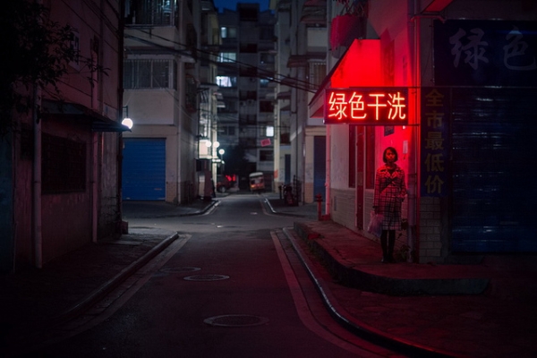 A woman stands under a red neon sign, in an empty street in Guilin, China on November 13, 2013. (金喜 刘/Flickr)