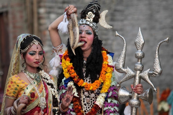 Indian Hindu devotees dressed as Hindu god Lord Shiva (R), seen holding a snake to his mouth, and Mata Parvati (L) participate in a procession on the eve of the Shivaratri festival in Jammu, India on February 26, 2014. (Strdel/AFP/Getty Images)