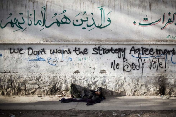 An Afghan homeless man sleeps under graffiti protesting against the upcoming presidential elections and the security agreement with the U.S. in Herat, Afghanistan on March 29, 2014. (Behrouz Mehri/AFP/Getty Images)