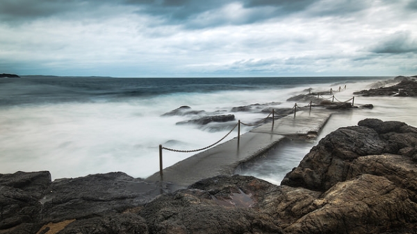 Misty waves crash over rocks in New South Wales, Australia on December 10, 2014. (Glen R90/Flickr)