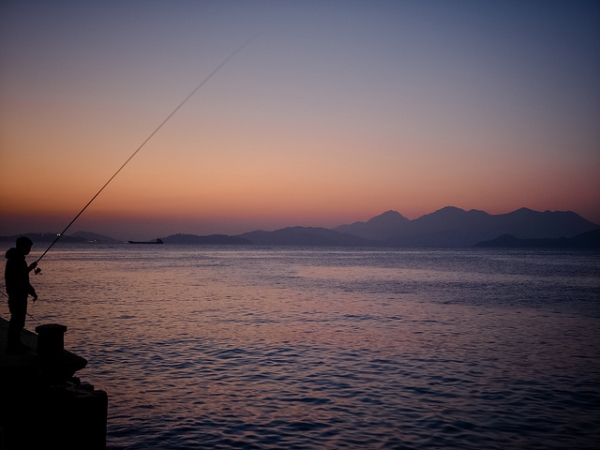 An avid angler waits for the fish to bite at sunset on Lamma Island, Hong Kong on January 3, 2015. (Os Ishmael/Flickr)