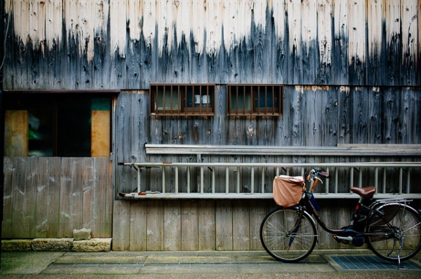 A bicycle is parked in front of a textured, wooden facade on the street in Shiga, Japan on January 5, 2015. (VisualAge/Flickr)