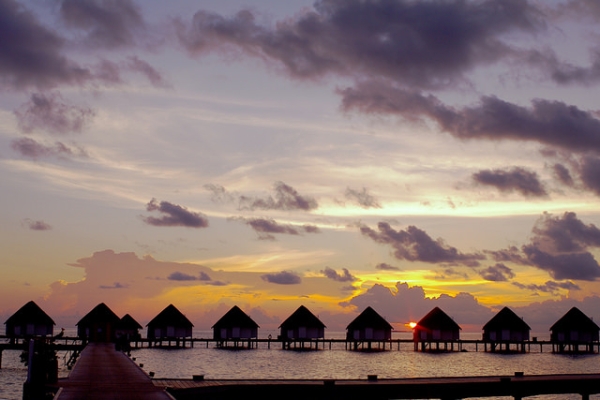 A row of houses stand silhouetted against the setting sun in Centara Grand Island, Maldives on May 1, 2015.(michibanban/Flickr)