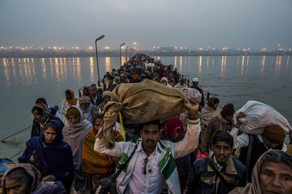  Hindu pilgrims walk across a pontoon bridge as others bathe on the banks of Sangam, the confluence of the holy rivers Ganges, Yamuna, and the mythical Saraswati, during the Maha Kumbh Mela on February 12, 2013 in Allahabad, India. (Daniel Berehulak/Getty Images)
