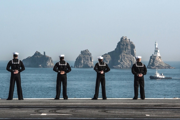 Four navy members stand facing the sea in Busan, South Korea on November 4, 2015. (Official U.S. Navy Page/Flickr)