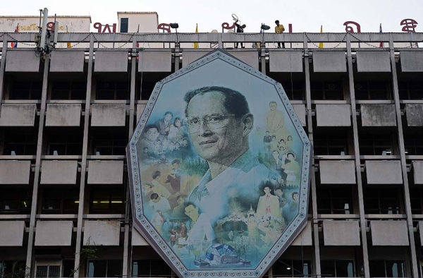 Workers use ropes to remove a portrait of King Bhumibol Adulyadej and install a new one on a facade as people gather at the Siriraj hospital where the King has been staying for months on the eve of his 88th birthday in Bangkok on December 4, 2015. (Christophe Archambault/AFP/Getty Images)