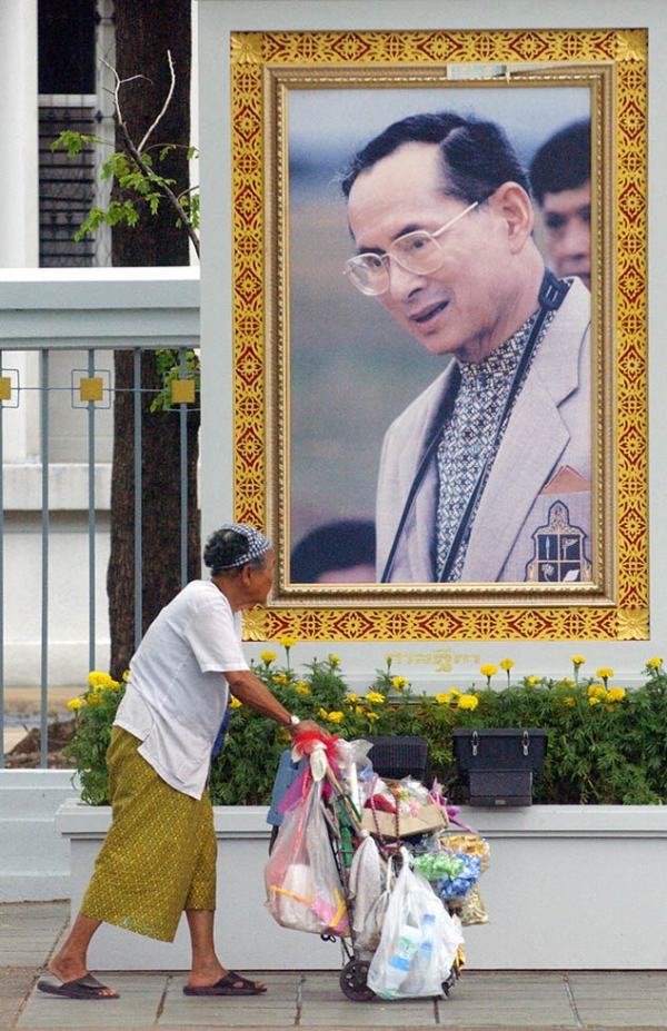 An elderly Thai woman walks past a portrait of King Bhumibol Adulyadej near the Grand Palace in Bangkok on June 10, 2006. (Adek Berry/AFP/Getty Images)