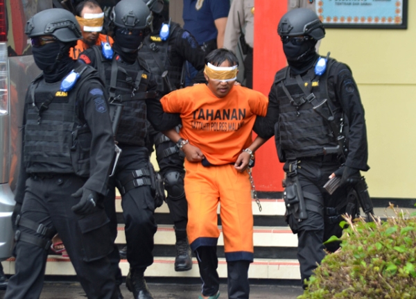 Indonesian anti-terror policemen transfer one of five men (C) following raids related to terror in Malang on February 21, 2016. (Aman Rochman/AFP/Getty Images)