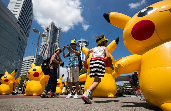 A girl runs past Pikachu- shaped balloons as a couple takes a photograph. (Tomohiro Ohsumi/Getty Images)