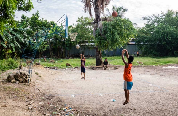 Two children quickly run on the court to shoot a few hoops while the adults are in action at the other end. Cebu, Philippines. (Richard James Daniels)
