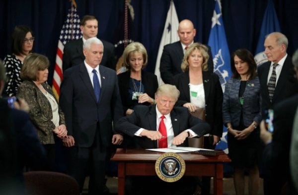 U.S. President Donald Trump (C) signs two executive orders during a visit to the Department of Homeland Security with Vice President Mike Pence, Homeland Security Secretary John Kelly and other officials January 25, 2017 in Washington, DC. (Chip Somodevilla/Getty Images)