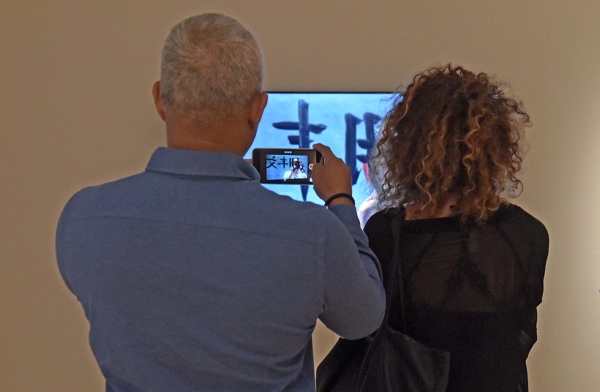 Members watch one of FX Harsono's pieces featured in the 'After Darkness: Southeast Asian Art in the Wake of History' exhibition at Asia Society New York on September 12, 2017. (Elsa Ruiz/Asia Society)