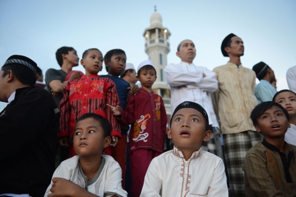 In anticipation of the Muslim fasting month of Ramadan, Indonesian boys and men await the sighting of the new moon from the rooftop of the Al-Hidayah Basmol mosque in Jakarta on July 8, 2013. (Romeo Gacad/AFP/Getty Images)