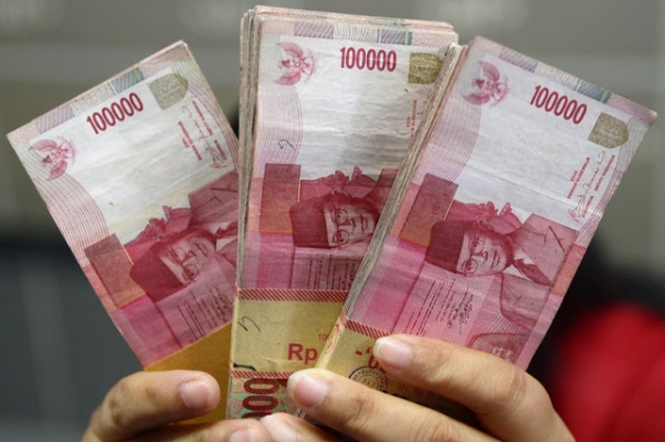 An Indonesian clerk holds stacks of Indonesian rupiah notes at a currency exchange office in Jakarta on Sept. 4, 2013. (Adek Berry/AFP/Getty Images) 