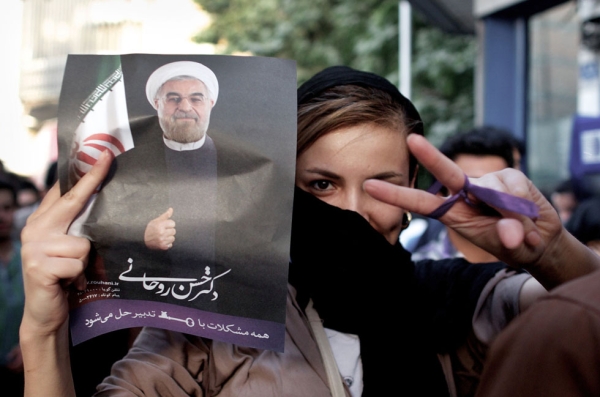 An Iranian woman flashes a victory sign as she holds a portrait of moderate presidential candidate Hassan Rouhani during celebrations in downtown Tehran, June 15, 2013. Iran's Interior Minister has said Rouhani won the election with 18.6 million votes, or 50.68 percent of the vote. (Behrouz Mehr/AFP/Getty Images)