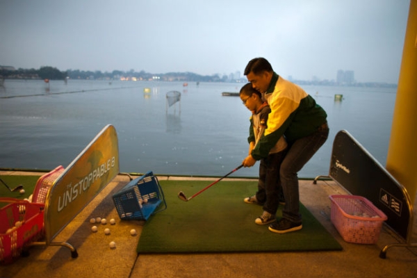 A father teaches his son how to golf at the Hanoi club golf center March 10, 2011 in Hanoi, Vietnam. (Paula Bronstein/Getty Images)