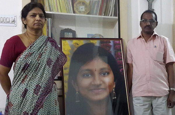 K. Shobha (left) and K. Krishna stand beside a portrait of their daughter, Kasarla Rishitha Reddy, who was among those killed in the Beas River flood. (Tom Lasseter/Bloomberg)