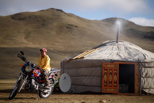 This picture taken on July 8, 2015 shows 13-year-old jockey Purevsurengiin Togtokhsuren sitting on a motorbike next to his 'yurt' (R) after taking care of the horses in Khui Doloon Khudag, some 50 kms west of Ulan Bator. (Johannes Eisele/AFP/Getty Images)