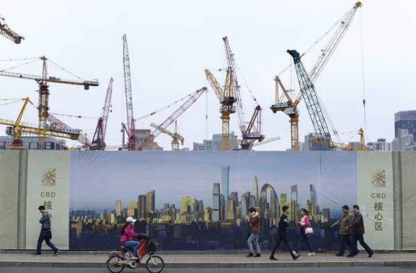 Pedestrians walk past a construction site in Beijing on April 1, 2015. (Wang Zhao/AFP/Getty Images)