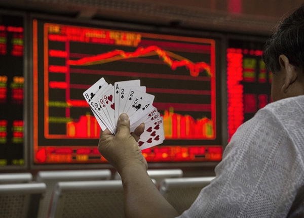 A Chinese day trader plays cards with others as he watches a stock ticker at a local brokerage house on August 27, 2015 in Beijing, China. (Kevin Frayer/Getty Images)