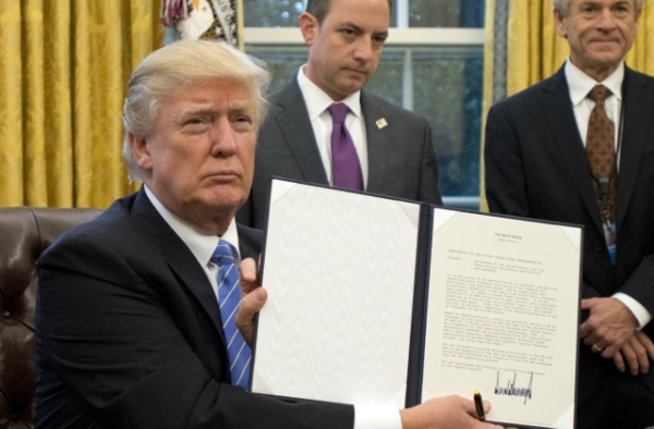 U.S. President Donald Trump shows the Executive Order withdrawing the US from the Trans-Pacific Partnership (TPP) after signing it in the Oval Office of the White House in Washington, DC on Monday, January 23, 2017. (Ron Sachs/Pool-Getty Images)