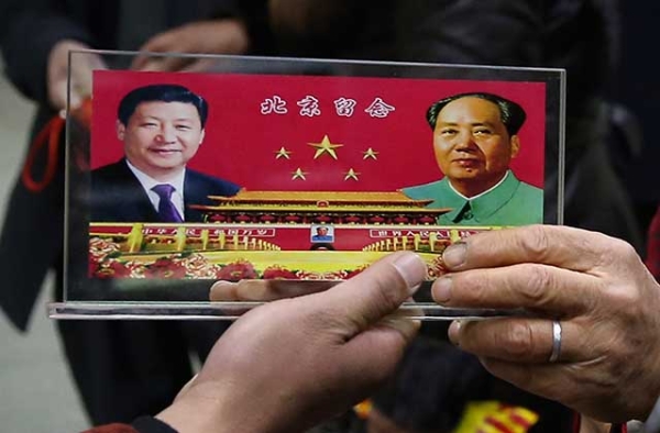 A vendor displays a souvenir with pictures of Chinese President Xi Jinping (Left) and the late Chinese Chairman Mao Zedong (Right) to visitors at the underpass outside the Great Hall of the People. (Feng Li/Getty)