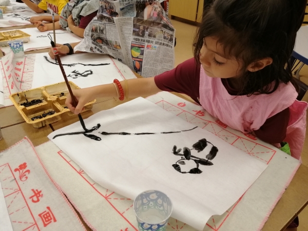 Kindergarten student practicing traditional ink brush painting