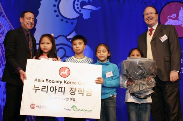 Alan Timblick, Head of the Seoul Global Center (far right) which partners with the ASKC Nuriati Scholarship Awardees, and Steven Herman, Seoul Bureau Chief of Voice of America (far left), on behalf of the SFCC that funded the ASKC Nuriati Scholarship, present students Ea Eam Hyun, Jin Woo Chun, Estherz Masigla, and Ezrahz Masigla (L-R) with prizes and gift certificates. (Asia Society Korea Center)