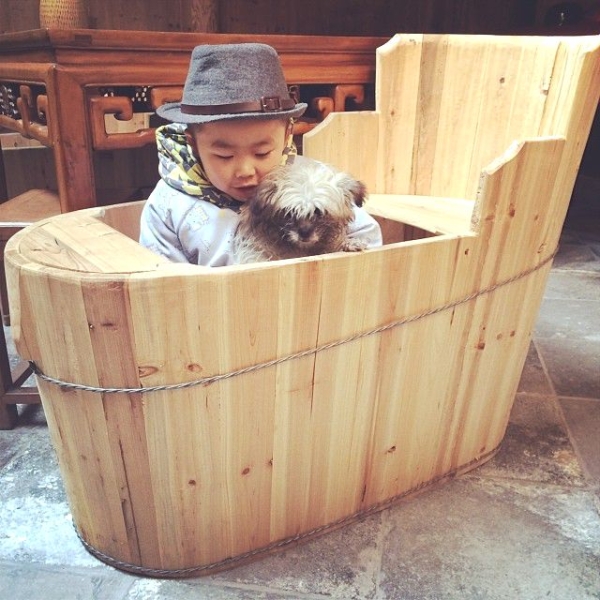 Tangtang, Ou Ning's fiance's son, sitting with his pet dog Gutou in a huotong, a local heating device made of a wooden barrel holding charcoal at the bottom. (Sun Yunfan)