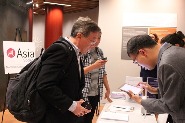 Alex Kwok (right) of ASNC assists a guest at check-in. (Yiwen Zhang/Asia Society)