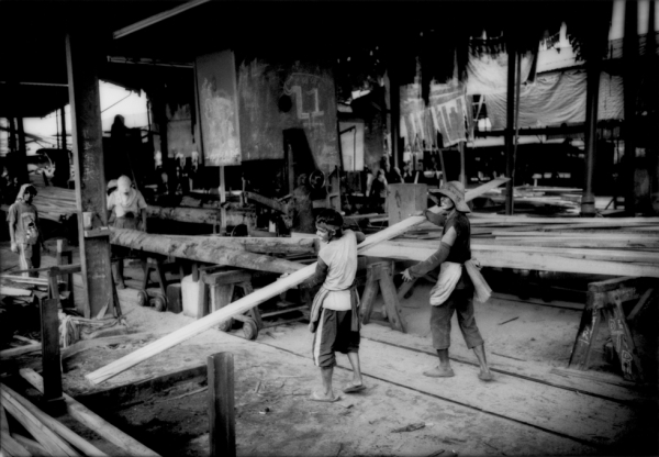 Workers cut logs from the Borneo rainforest into planks of lumber for export in one of the sawmills that line the banks of Batan. (James Whitlow Delano) 