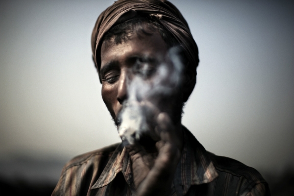 A miner smokes a cigarette during a rare break. (Erik Messori)