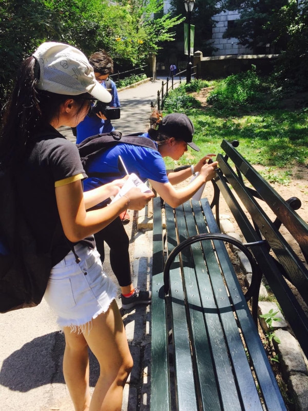 Young Scholar Dang Weikun takes a picture of a Central Park bench plaque while Young Scholar Liang Qiqi keeps track of all the bench plaques they have documented thus far. (Zhangbolong Liu & Zhu Xi/New York)