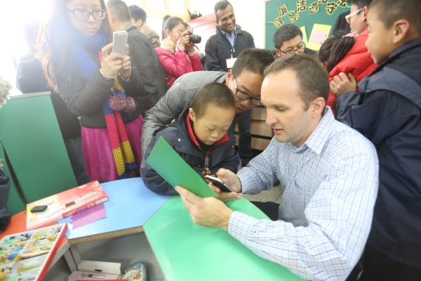 Global Leadership Initiatives Executive Director, Michael G. Kulma talks to a child during a public service site visit with the Asia 21 Young Leaders.