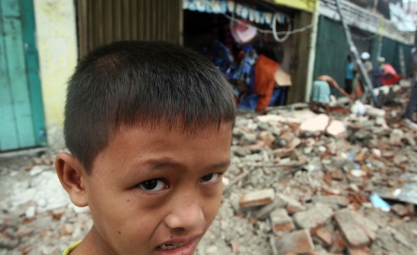 A child stands outside a collapsed building after an earthquake October 1, 2009 in Padang, West Sumatra, Indonesia.  A second quake struck some 12 hours later, 150 miles from Padang.