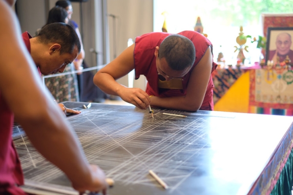 The monks draw an outline of the mandala on the wooden platform. (Jessica Ngo)